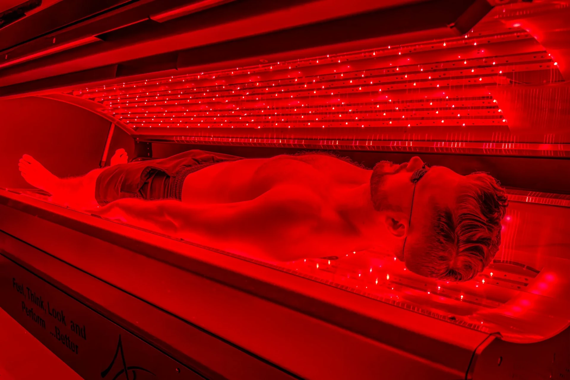 Man using full-body red light therapy Pro-Bed for muscle recovery at REDSOL Wellness Club League City TX